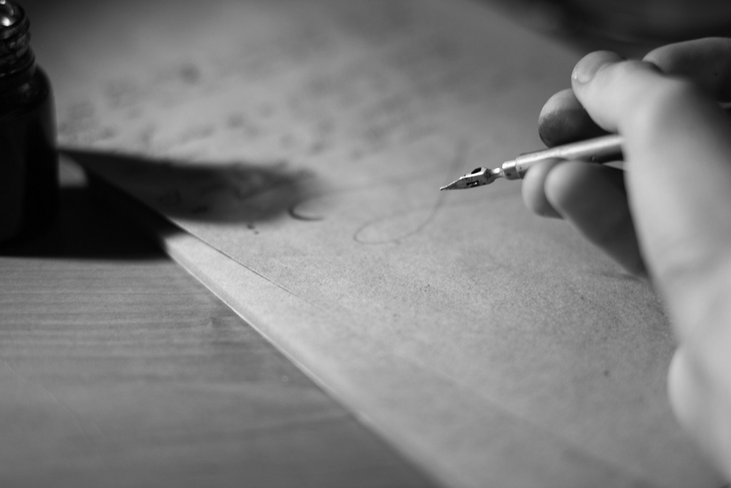 A hand writing a letter with a quill