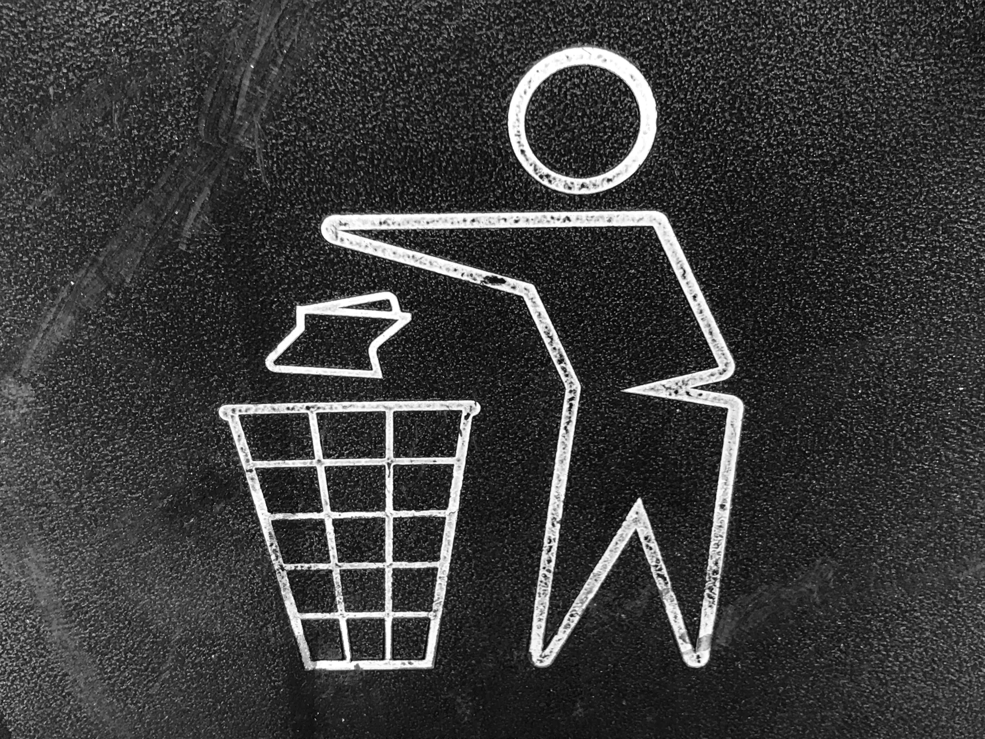 A sign depicting a person throwing trash into a bin.