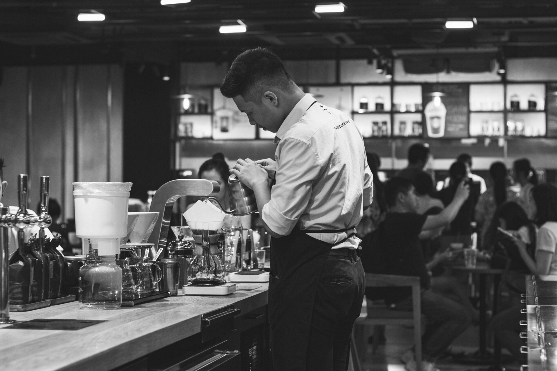 A barista brews a Chemex at a coffee bar.