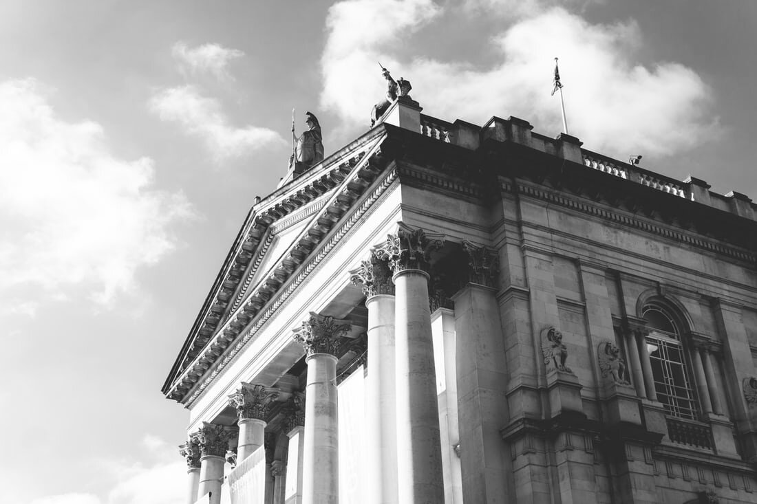 The Tate Britain museum building from a low angle in front of a cloud speckled sky