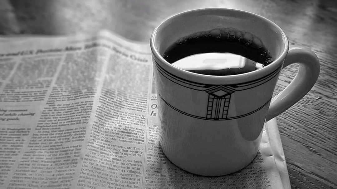 A diner mug rests on a folded newspaper sitting on a table. Via me.