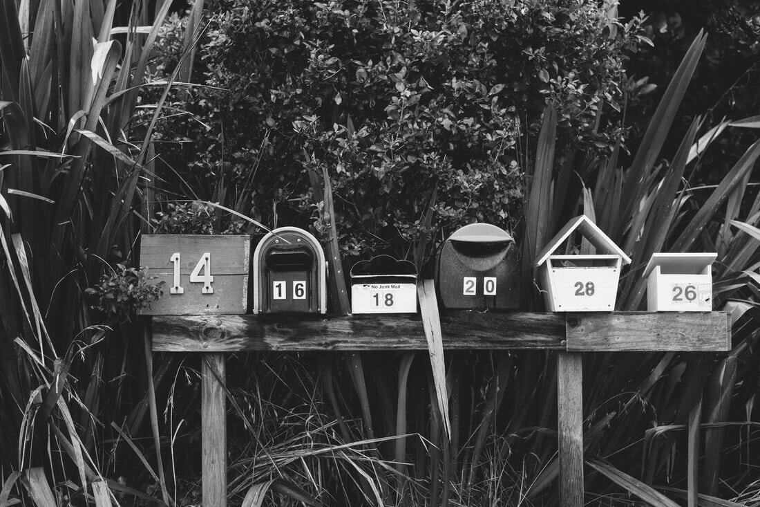 A collection of mailboxes on a wooden stand. Via Unsplash.