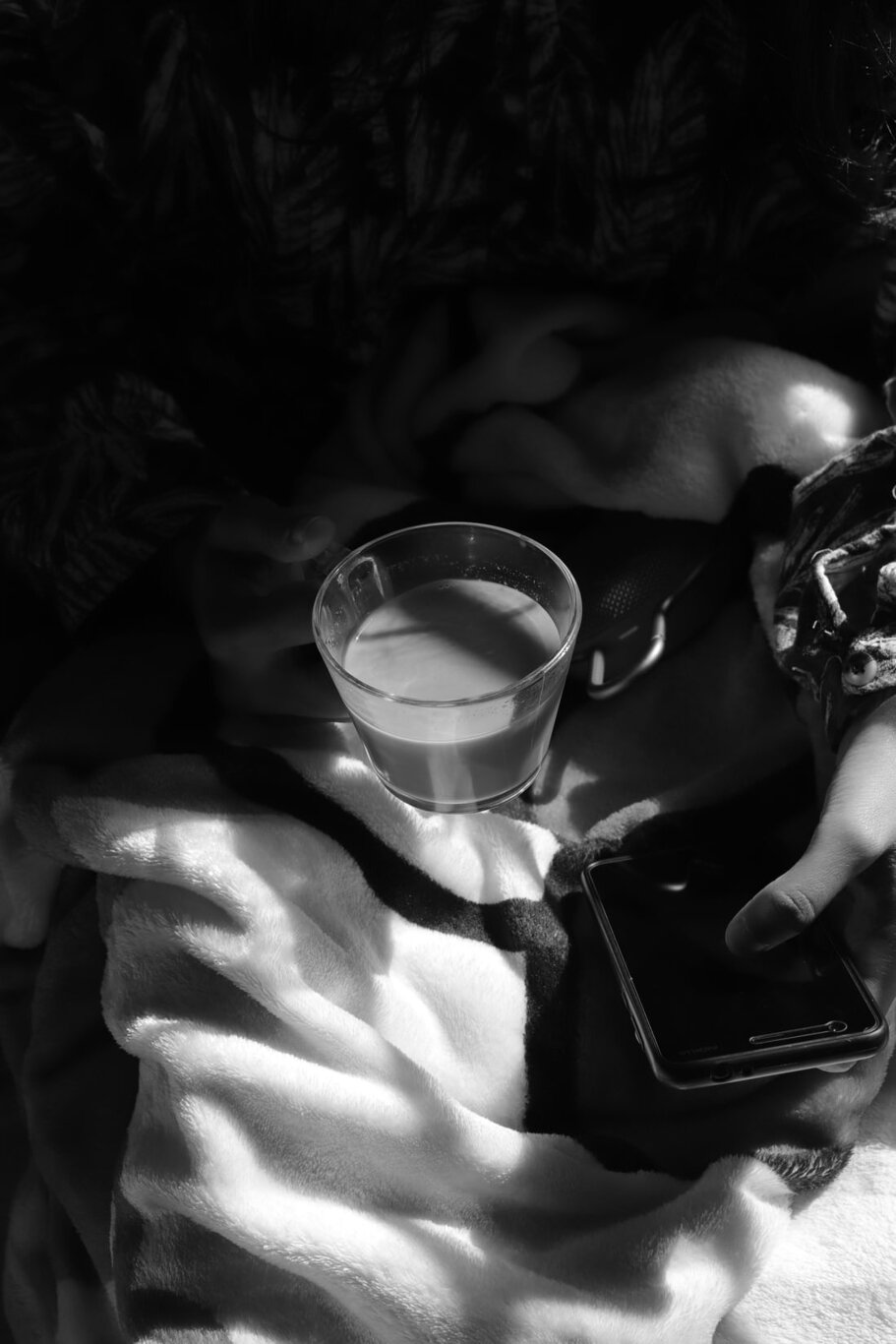 A person looks at the their phone while holding a cup of coffee in close-up. Via Unsplash.