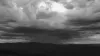 Mountains in silhouette with dark clouds and rain above