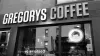 The front of Gregorys Coffee in New York City, featuring a big sign and dark hair and glasses logo