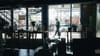 The interior of a darkened coffee shop looking out to a sunny street